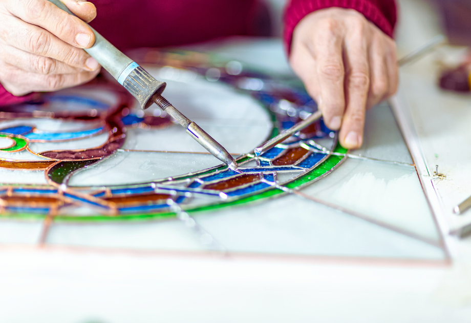 hands adding solder to a stain glass work