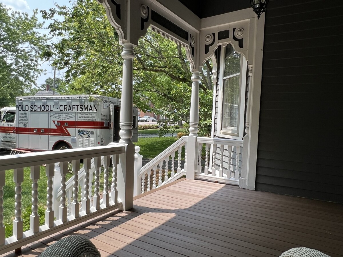 a Victorian style front porch with a truck in the driveway